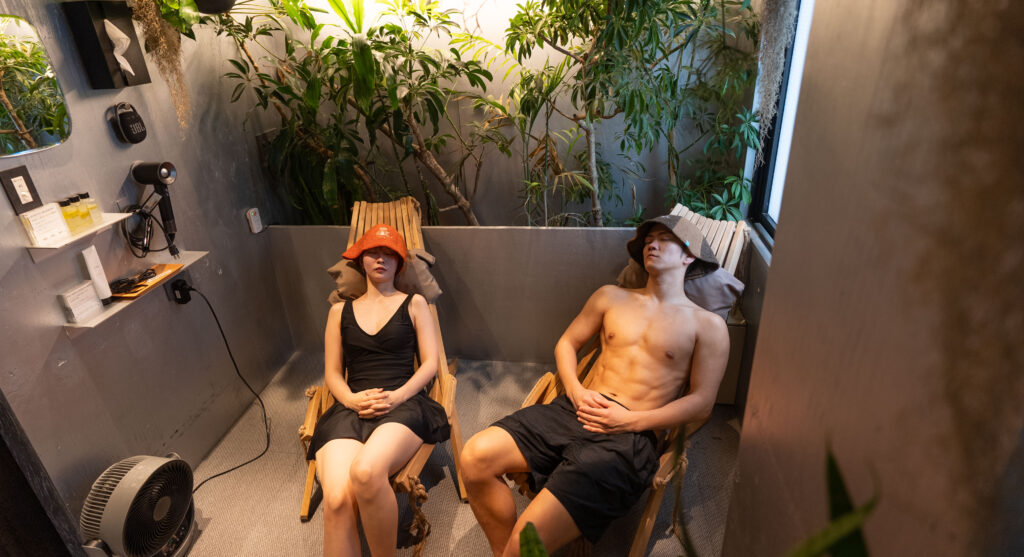SAUNA&coの個室サウナで休憩を楽しむ男女。植物に囲まれた洗練された空間